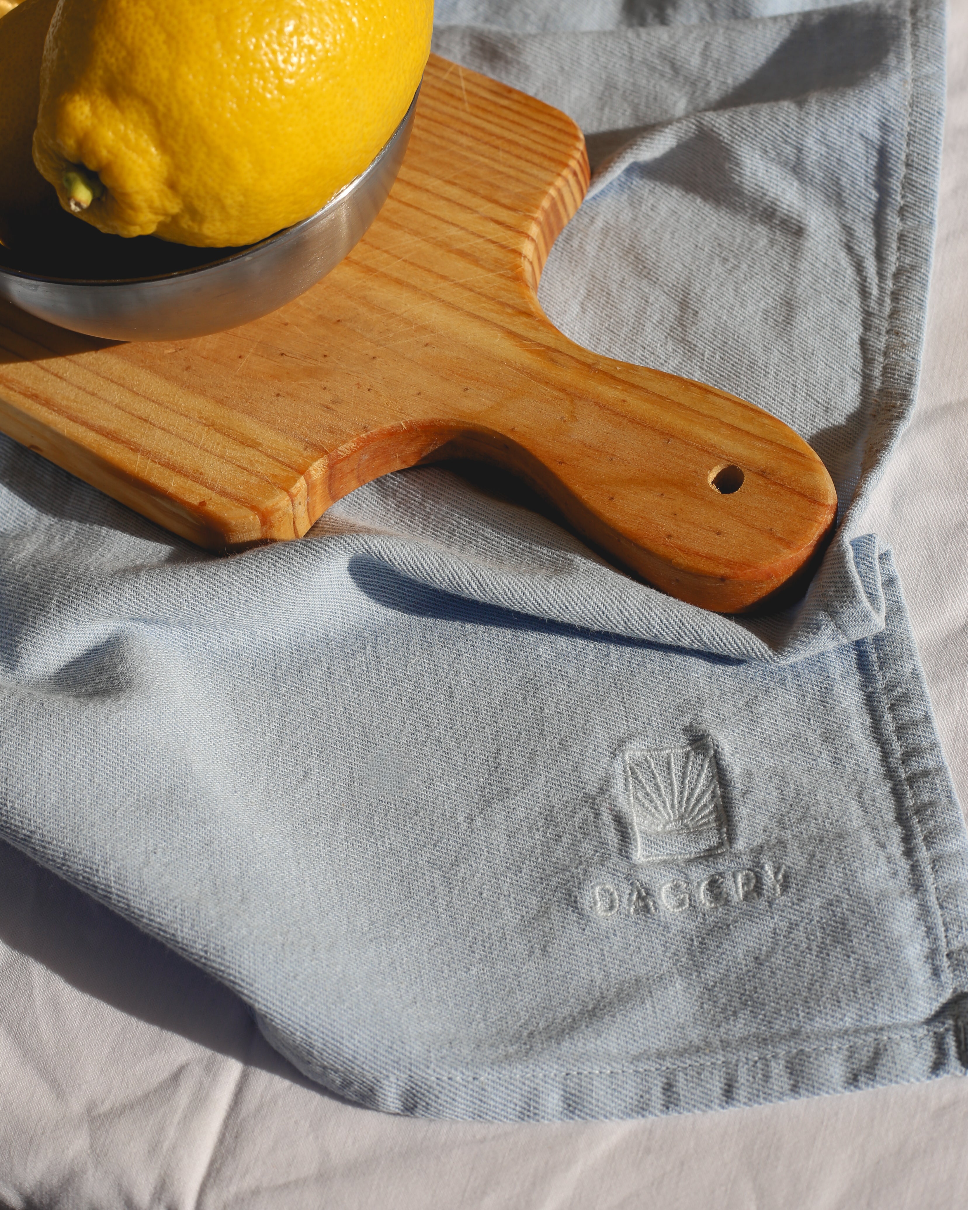 Wooden cutting board with a lemon on a gray cloth with Decoy logo