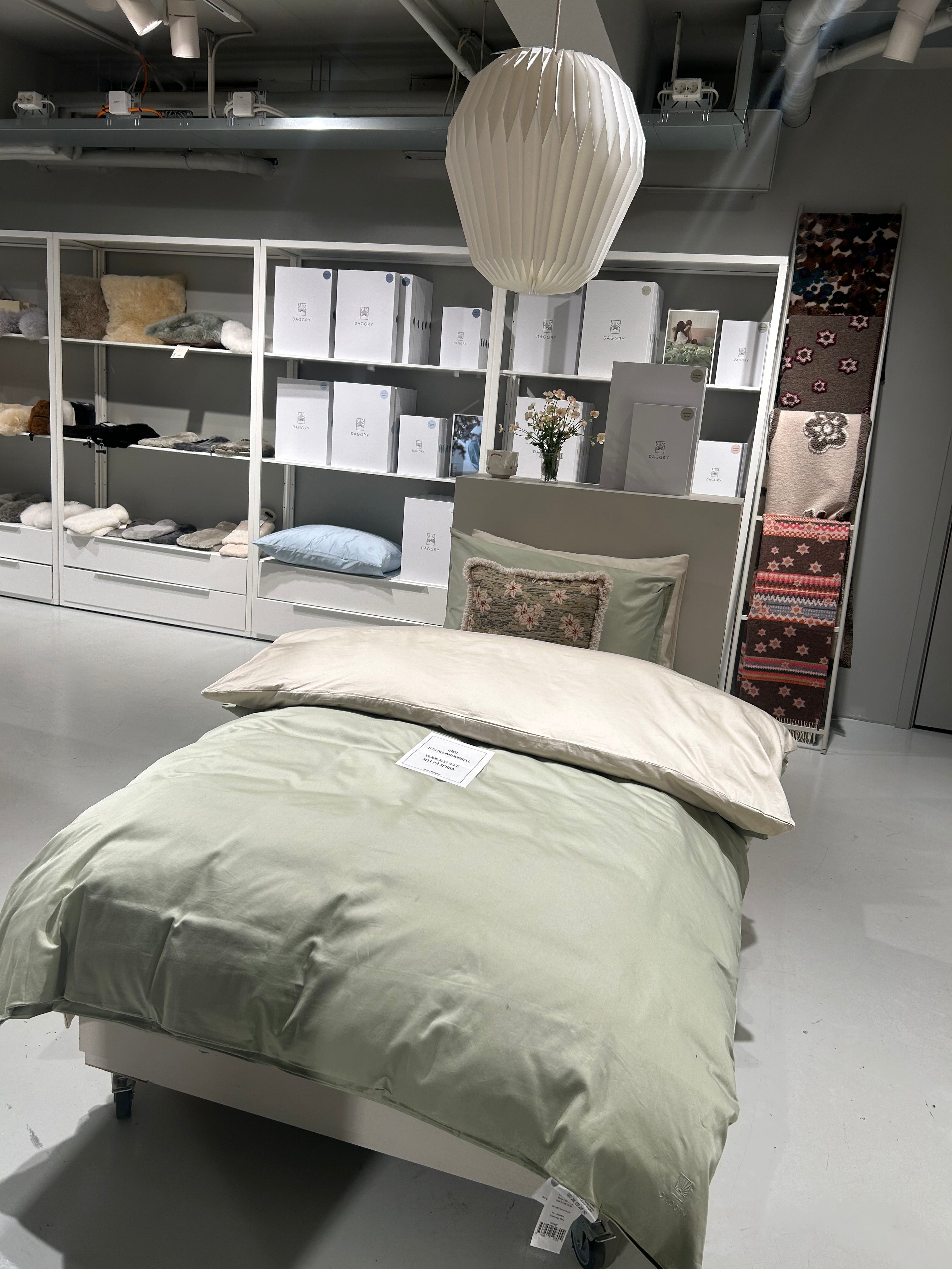 Bedroom with a bed featuring green bedding and pillows, a lamp, and shelves with decor.