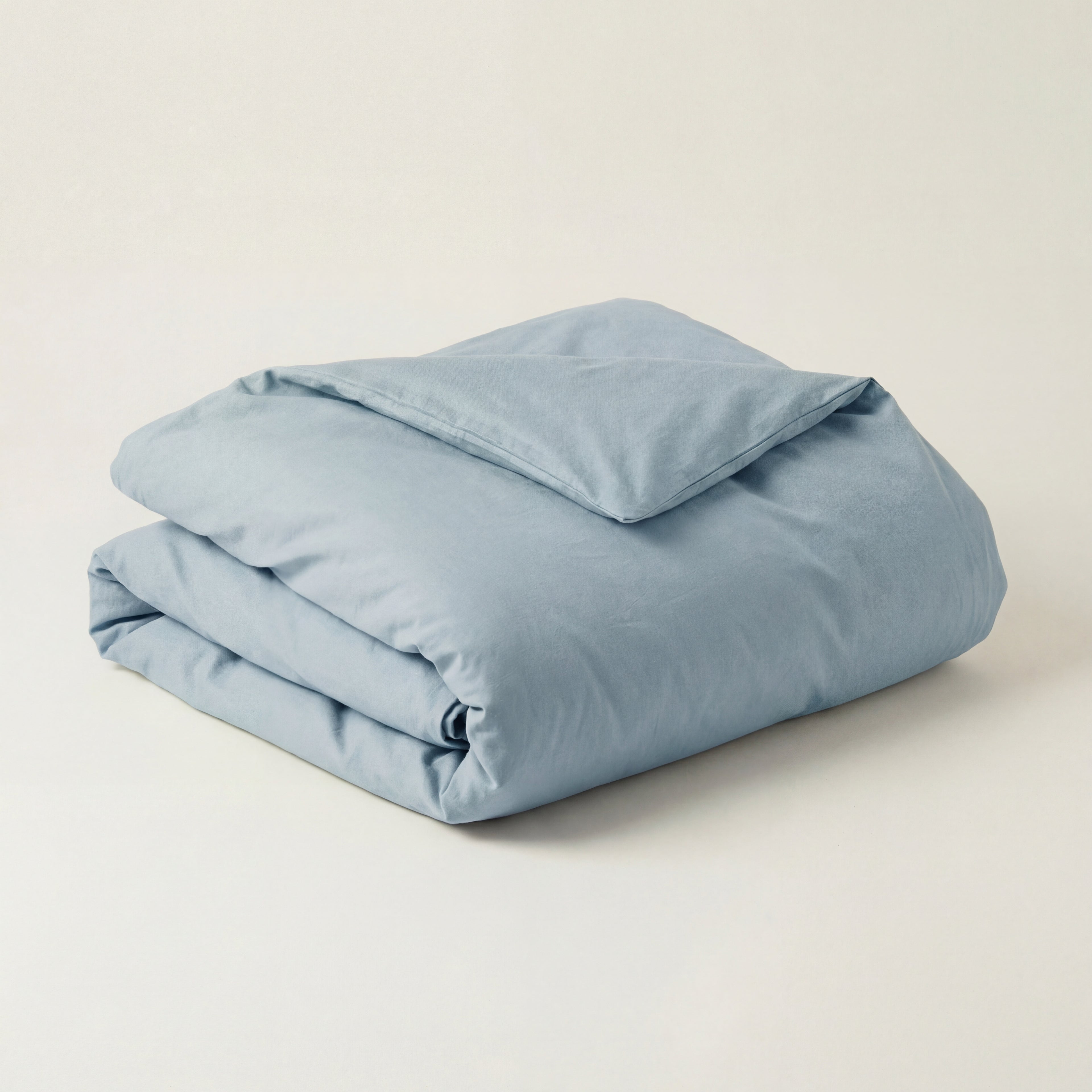 Folded morning blue duvet on a beige background