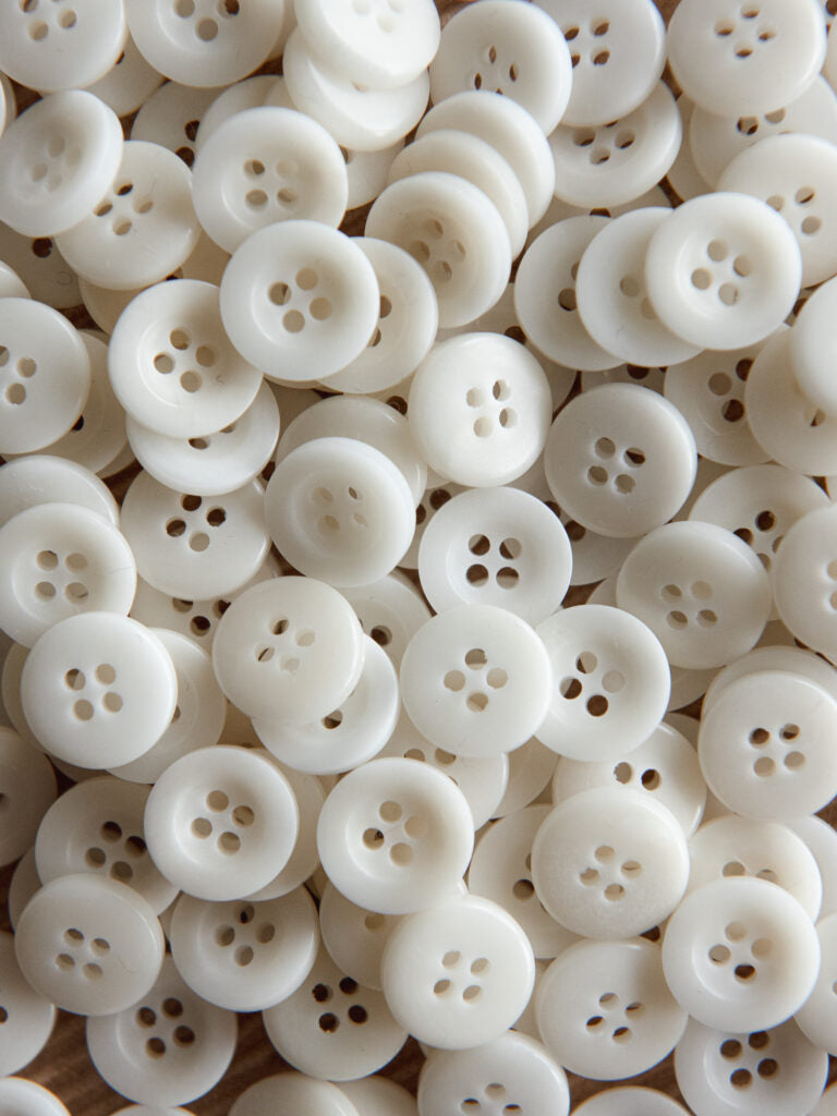 Close-up of a large pile of white buttons with four holes.
